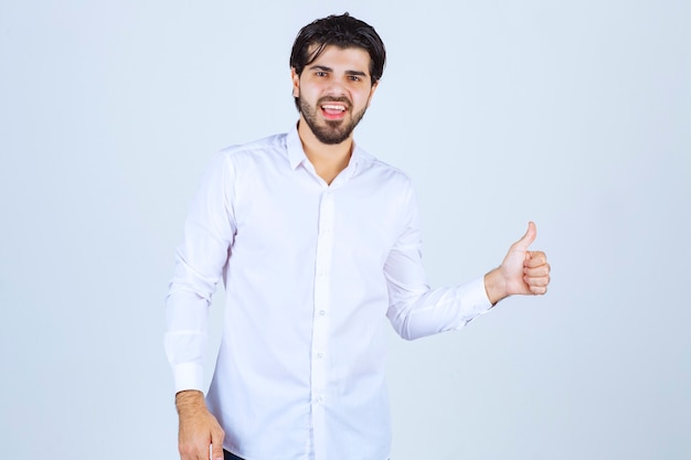 Hombre con una camisa blanca que muestra el signo de la mano de disfrute