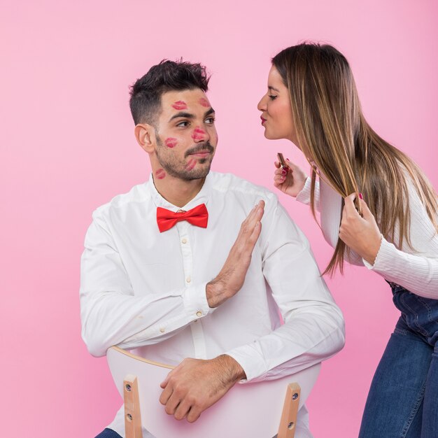 Hombre en camisa blanca rechazando besos de mujer