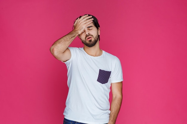 El hombre con camisa blanca siente sueño y cierra los ojos.