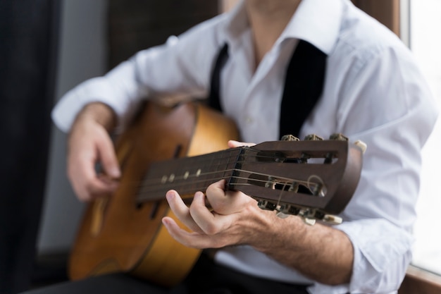 Foto gratuita hombre de camisa blanca tocando el primer plano de la guitarra