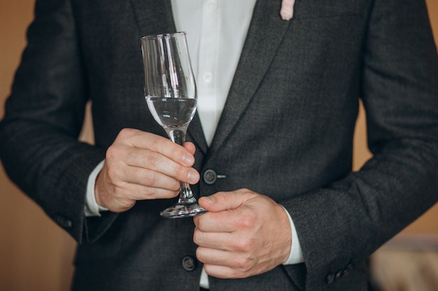 hombre en una camisa blanca con un vaso de champán muestra