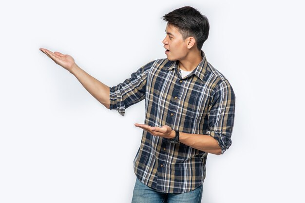 Hombre con una camisa a cuadros apuntando sus manos hacia un lado