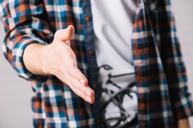 Hombre en camisa a cuadros ofreciendo mano