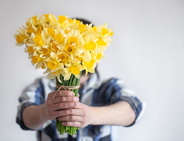 Un hombre con una camisa cubre su rostro con un ramo de flores.