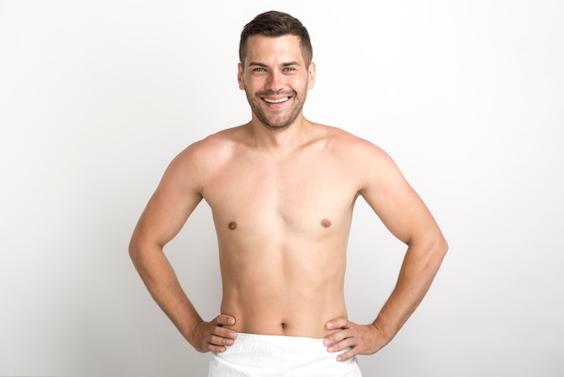 Foto gratuita hombre sin camisa feliz posando contra la pared blanca