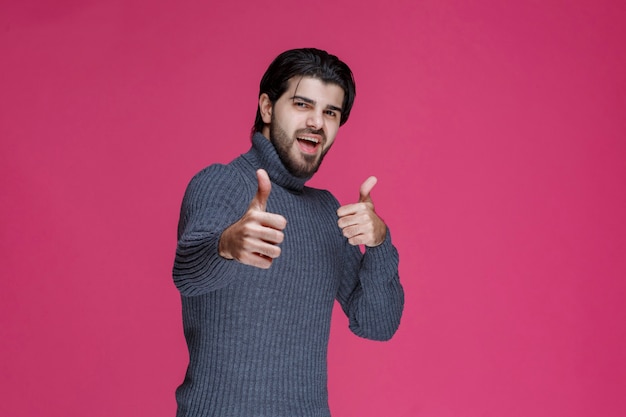 Hombre de camisa gris haciendo señal de mano de disfrute.