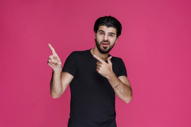 Hombre con camisa negra apuntando a algo o presentando a alguien