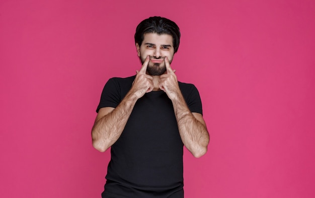 Foto gratuita hombre de camisa negra apuntando a una cara alegre