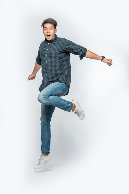 Foto gratuita el hombre con camisa oscura y jeans saltó de alegría