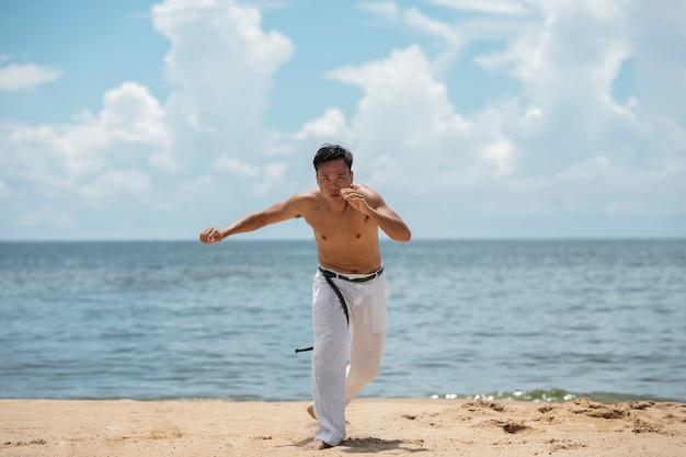 Foto gratuita hombre sin camisa practicando capoeira solo en la playa