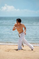 Foto gratis hombre sin camisa practicando capoeira solo en la playa