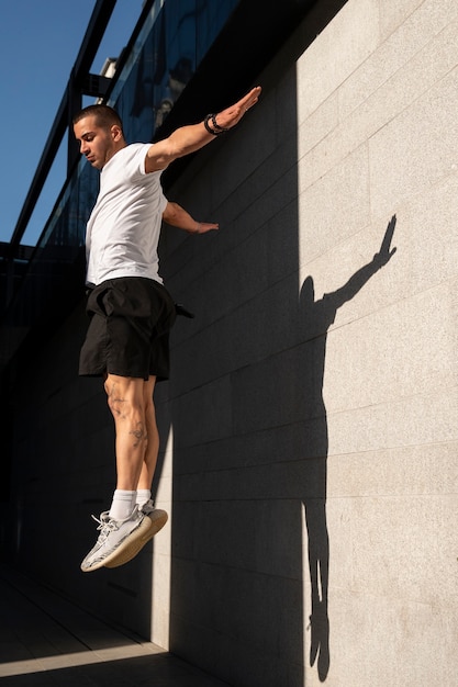 Foto gratuita hombre sin camisa practicando parkour al aire libre