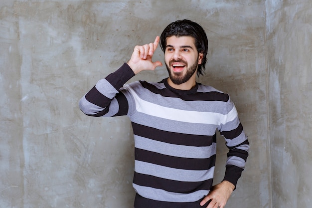 Foto gratuita hombre de camisa a rayas apuntando a algo a un lado