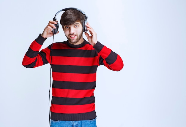 Foto gratuita hombre de camisa a rayas rojas quitándose los auriculares para escuchar voces externas.