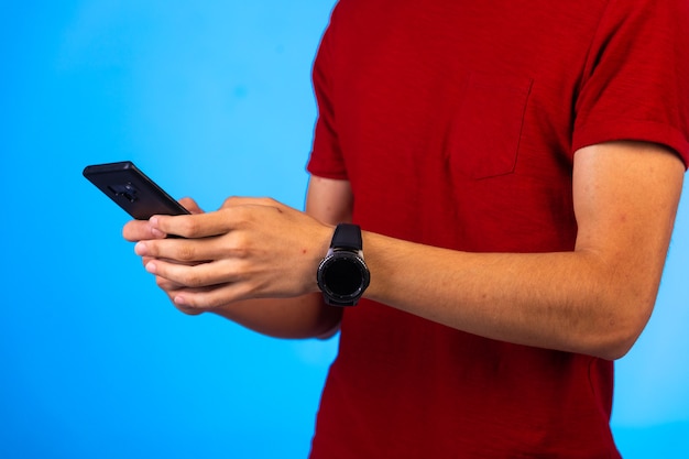 Hombre de camisa roja sosteniendo y charlando en un teléfono inteligente.