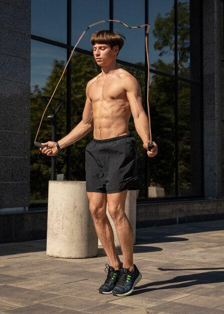 Hombre sin camisa saltando la cuerda al aire libre