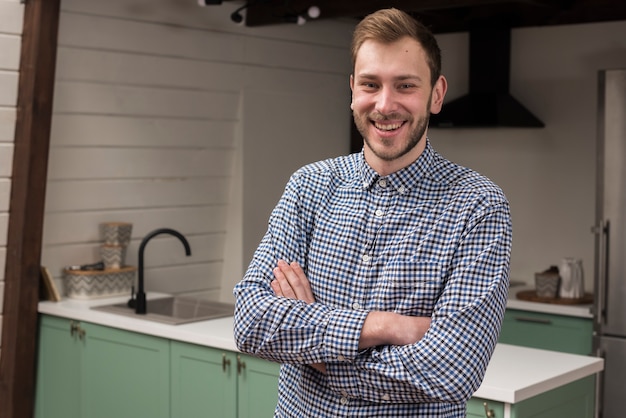 Hombre en camisa sonriendo y posando en la cocina