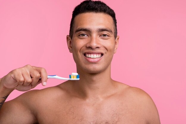 Foto gratuita hombre sin camisa sonriente con cepillo de dientes