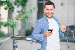 Foto gratuita hombre en camisa con teléfono cerca de barandilla