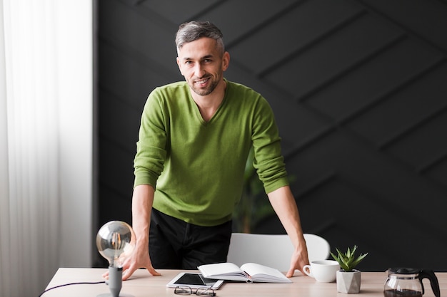 Foto gratuita hombre en camisa verde de pie detrás de un escritorio