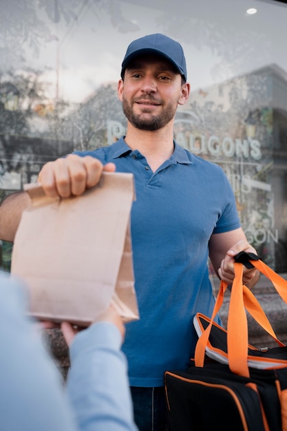 Hombre en camiseta entregando comida para llevar