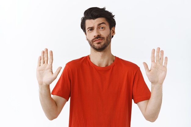 Hombre de camiseta roja levanta las manos para detener algo