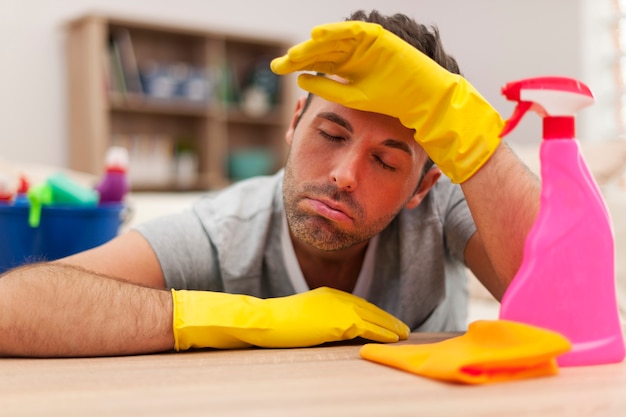 Hombre cansado con equipo de limpieza