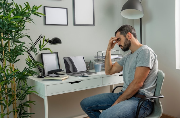 Foto gratuita hombre cansado sentado en el escritorio de su casa