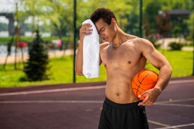 Hombre cansado sosteniendo una pelota de tiro medio