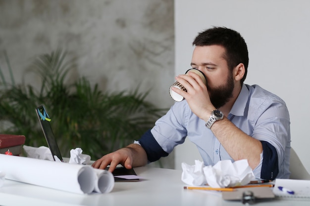 Hombre cansado en el trabajo, tomando café