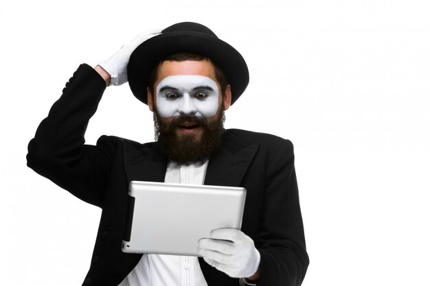 Hombre con una cara mime trabajando en la computadora portátil