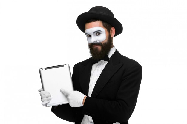 Hombre con una cara mime trabajando en la computadora portátil