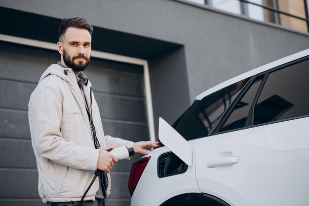 Hombre cargando auto eléctrico por la casa