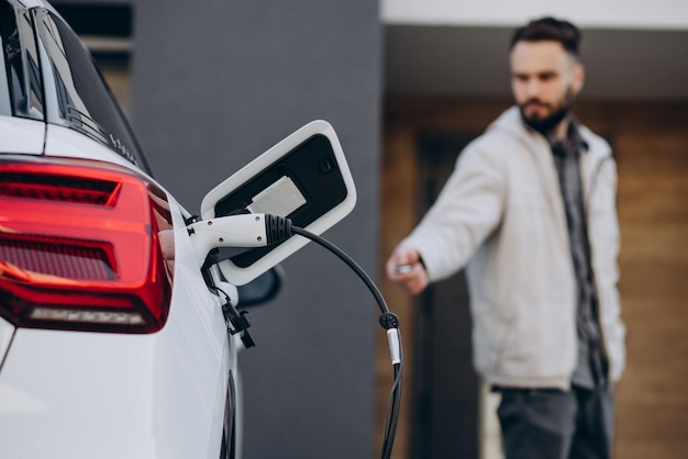 Hombre cargando auto eléctrico por la casa