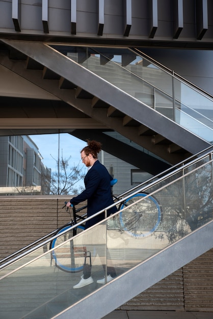 Foto gratuita hombre cargando bicicleta por las escaleras tiro completo