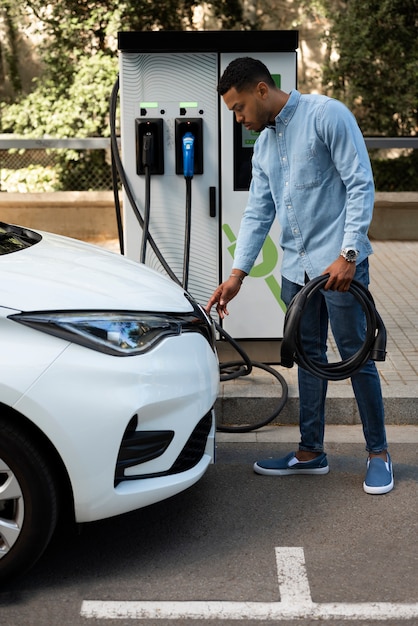 Foto gratuita hombre cargando coche eléctrico tiro completo