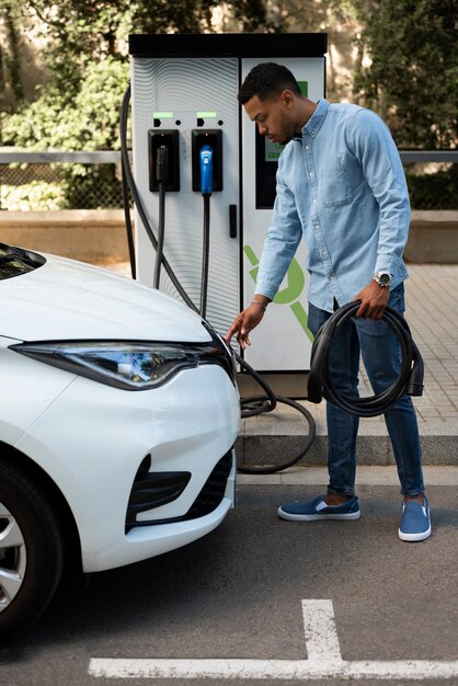 Hombre cargando coche eléctrico tiro completo