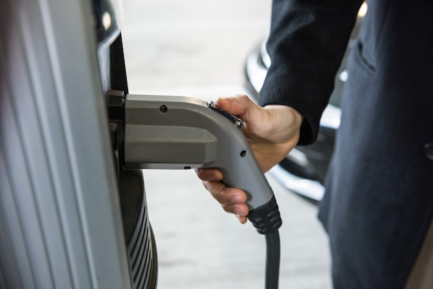 Hombre cargando el coche en la estación de carga de vehículos eléctricos