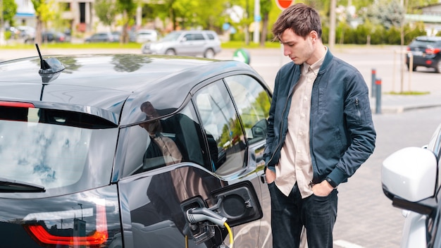 Hombre cargando su coche eléctrico en la estación de carga