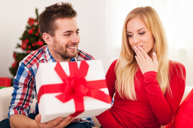 Hombre cariñoso dando a su novia regalo de Navidad