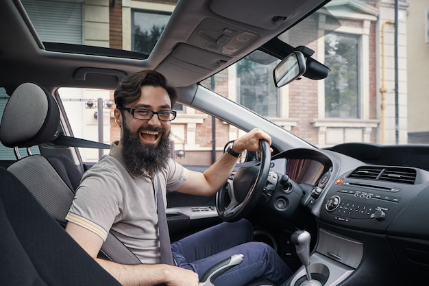 Hombre carismático feliz conduciendo un automóvil