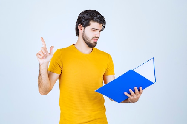 Hombre con carpeta azul apuntando hacia arriba.