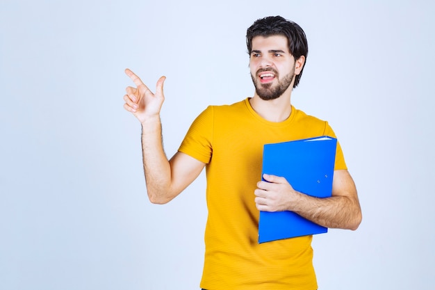 Hombre con carpeta azul apuntando hacia arriba.