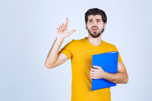 Hombre con carpeta azul apuntando hacia arriba.