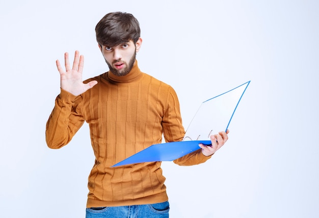 Hombre con una carpeta azul deteniendo algo.