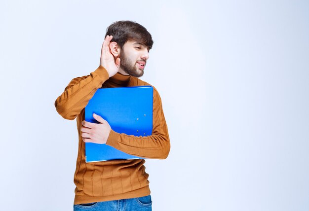 Hombre con una carpeta azul escuchando atentamente.