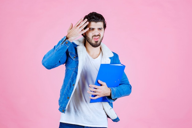 Foto gratuita el hombre con una carpeta azul parece aterrorizado y cansado