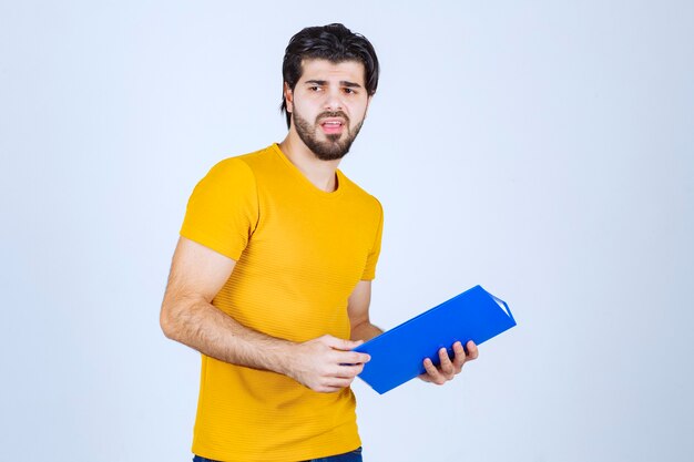 Foto gratuita el hombre con una carpeta azul parece confundido o inexperto.