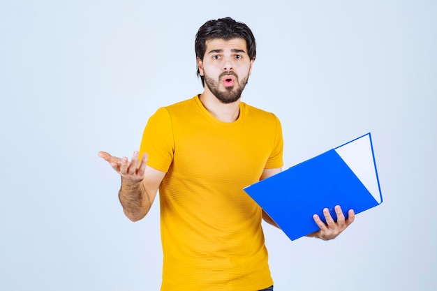 El hombre con una carpeta azul parece confundido o inexperto.