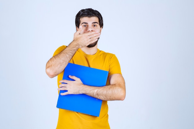 Foto gratuita el hombre con una carpeta azul parece confundido o inexperto.